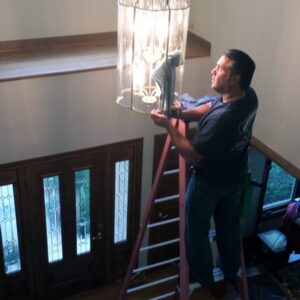 Photo of Powerhouse Pete cleaning a chandelier while on a ladder