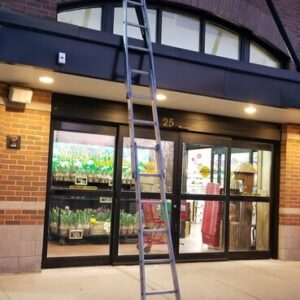 Photo of a Trader Joe's storefront with a ladder showing a recently cleaned and restored sign and windows