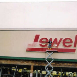 Photo of Powerhouse Pete power washing a Jewel store sign while on a lift