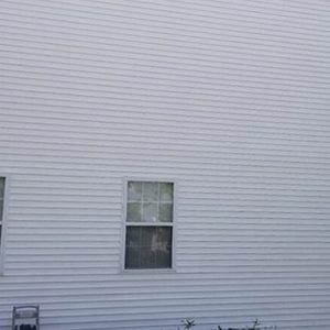 After photo of vinyl siding on the side of a house with two windows that was soft washed cleaned
