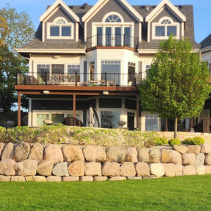 Photo of a large residential house with a retaining wall made out of boulders