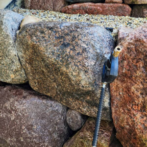 Photo of a boulder retaining wall with a power washing wand resting on it