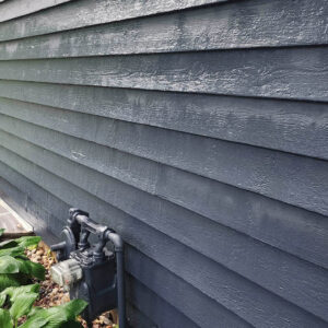 Photo of residential dark colored wood siding after being soft power washed